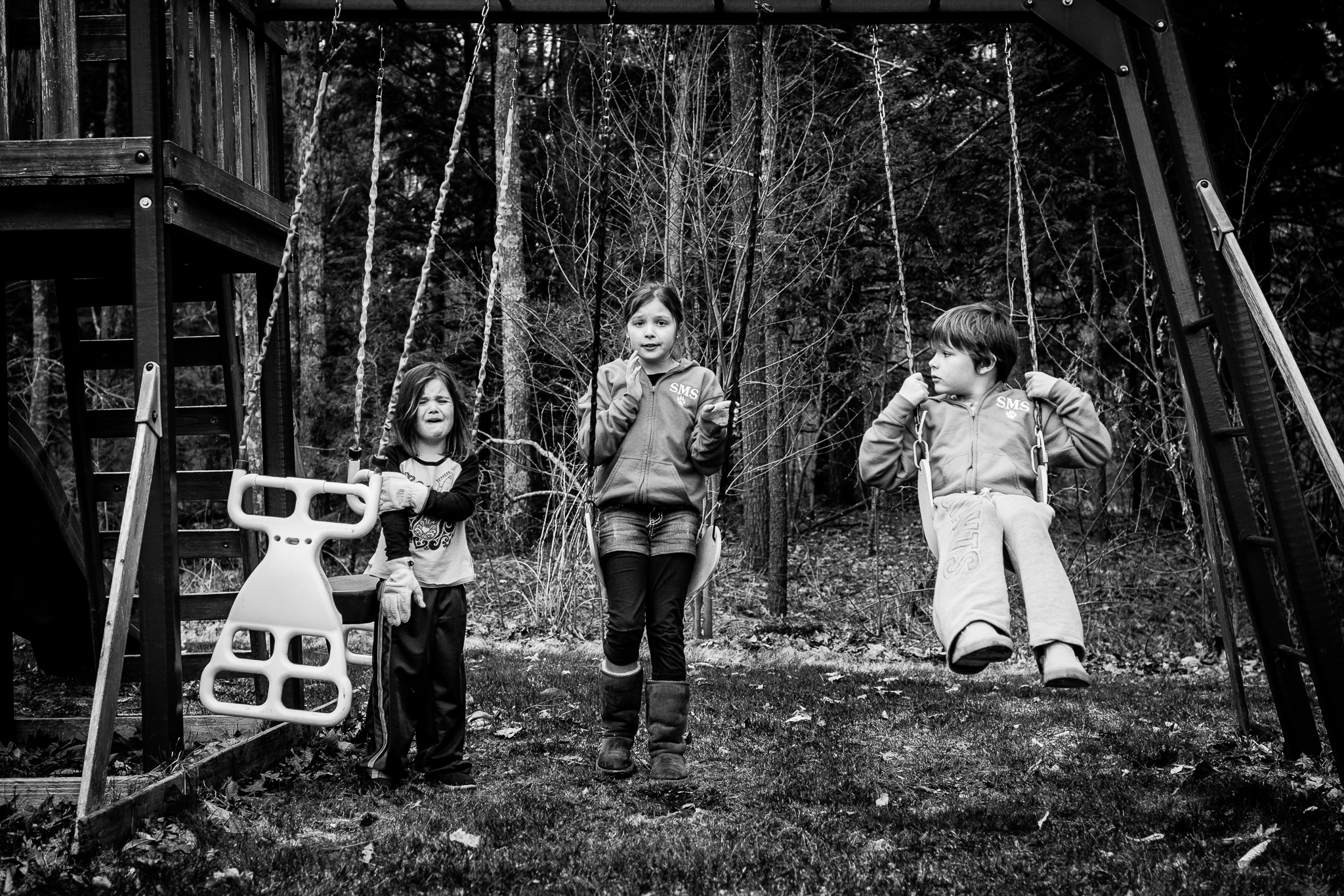 little girl hurt on swings with siblings looking on