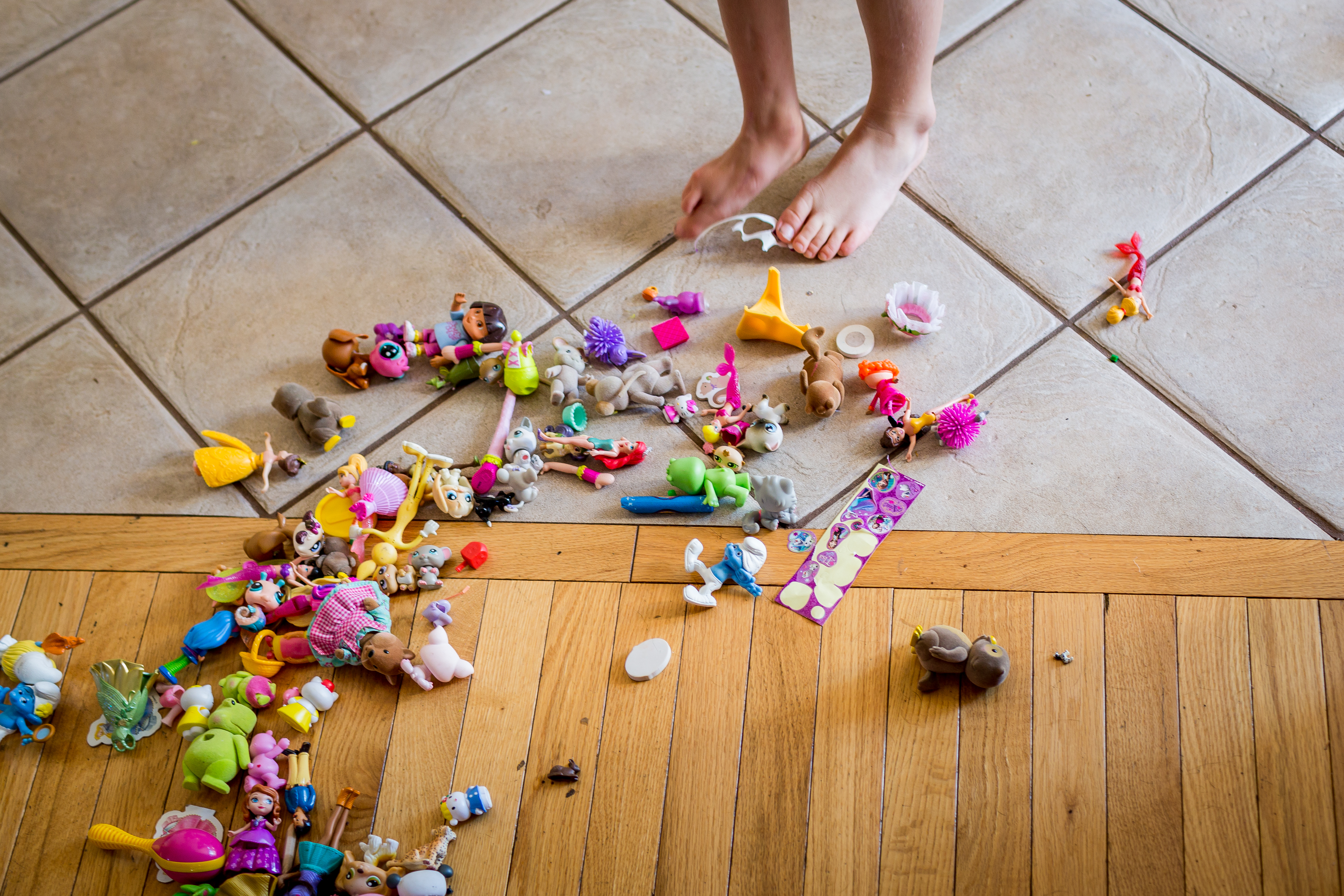 child's feet standing next to a pile of toys