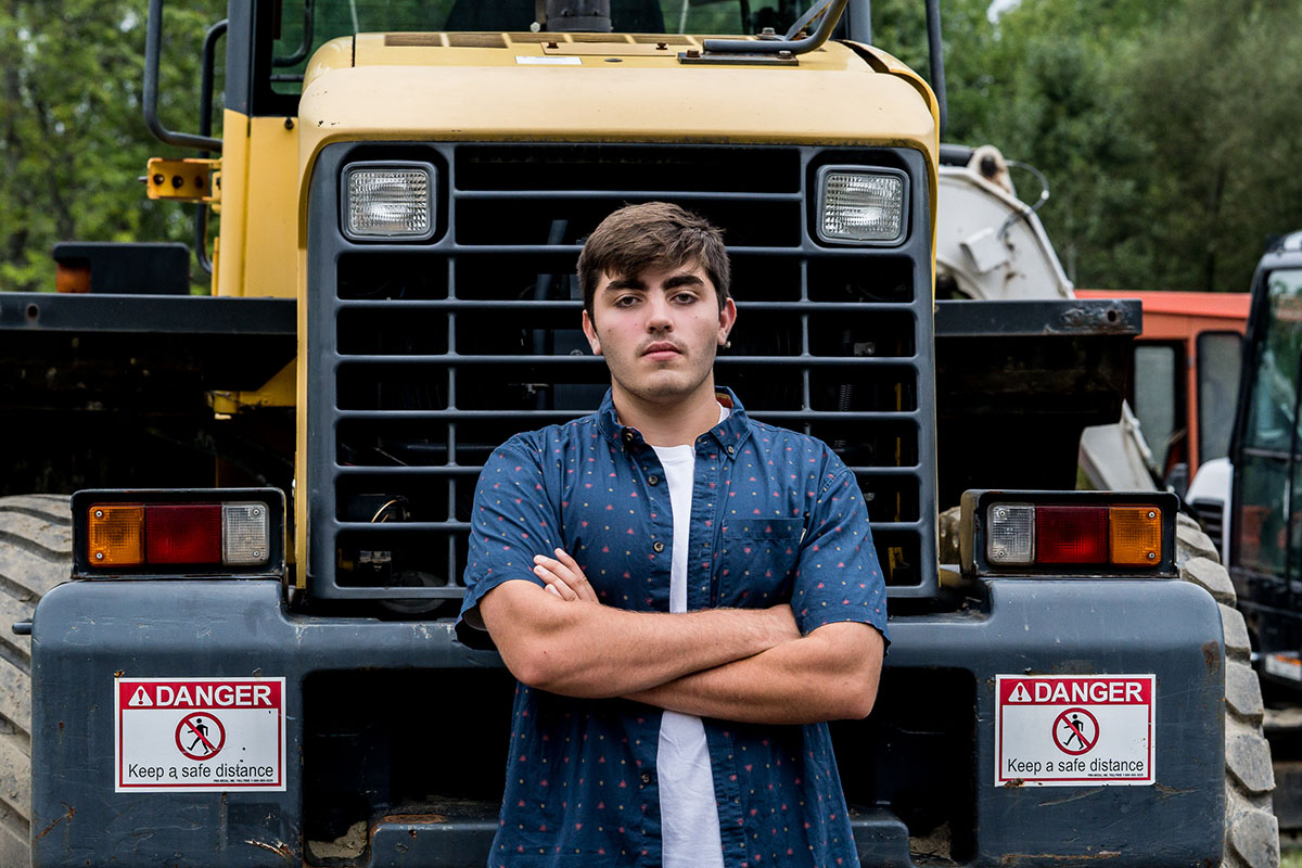 senior boy standing with arms crossed in front of truck